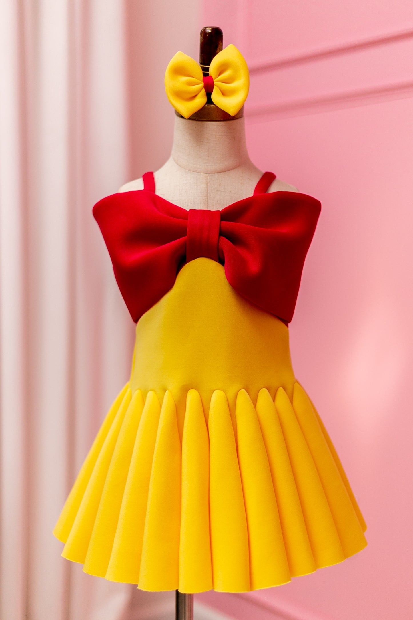 Fuchsia pink and yellow big bow dress displayed on design stand