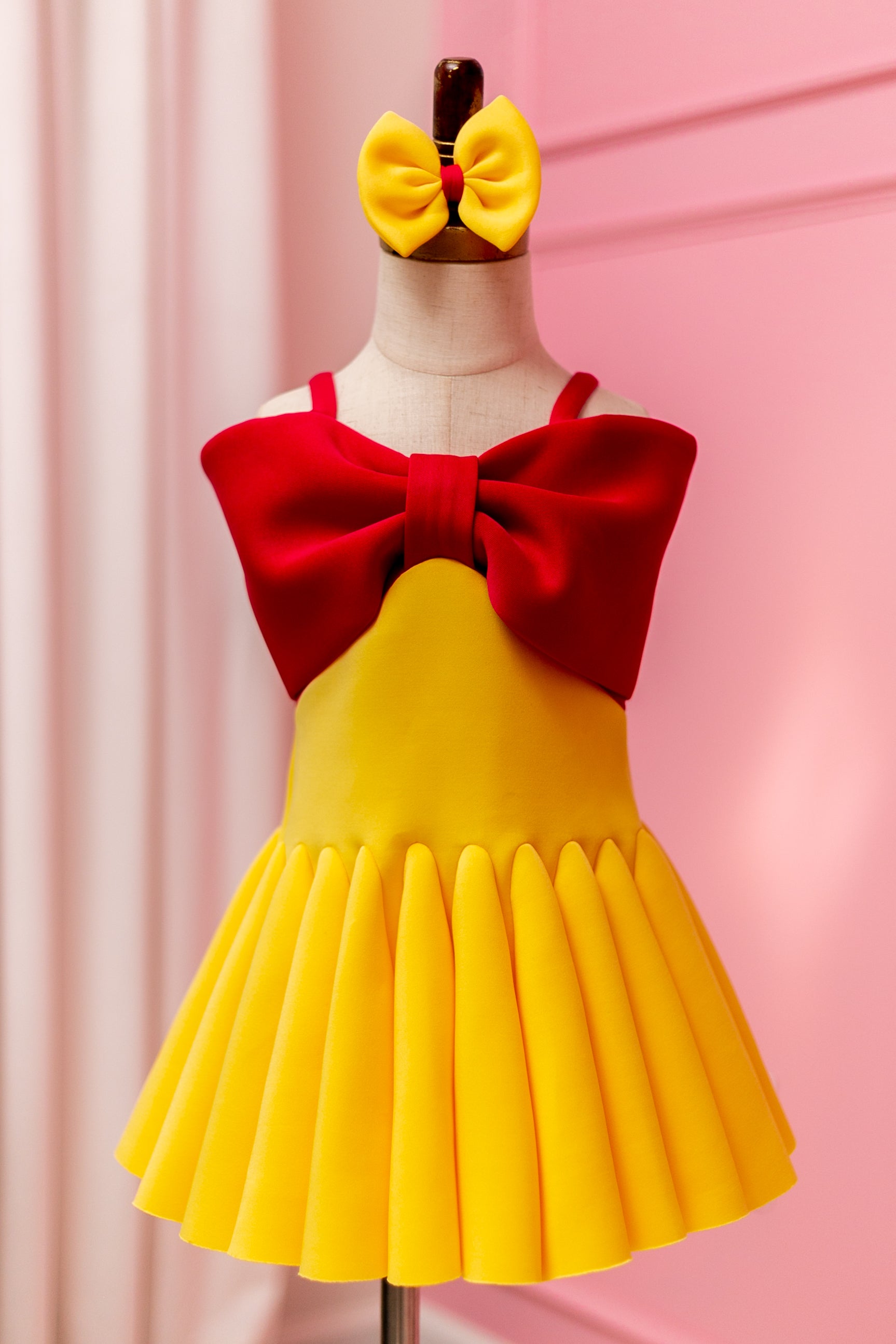 Fuchsia pink and yellow big bow dress displayed on design stand