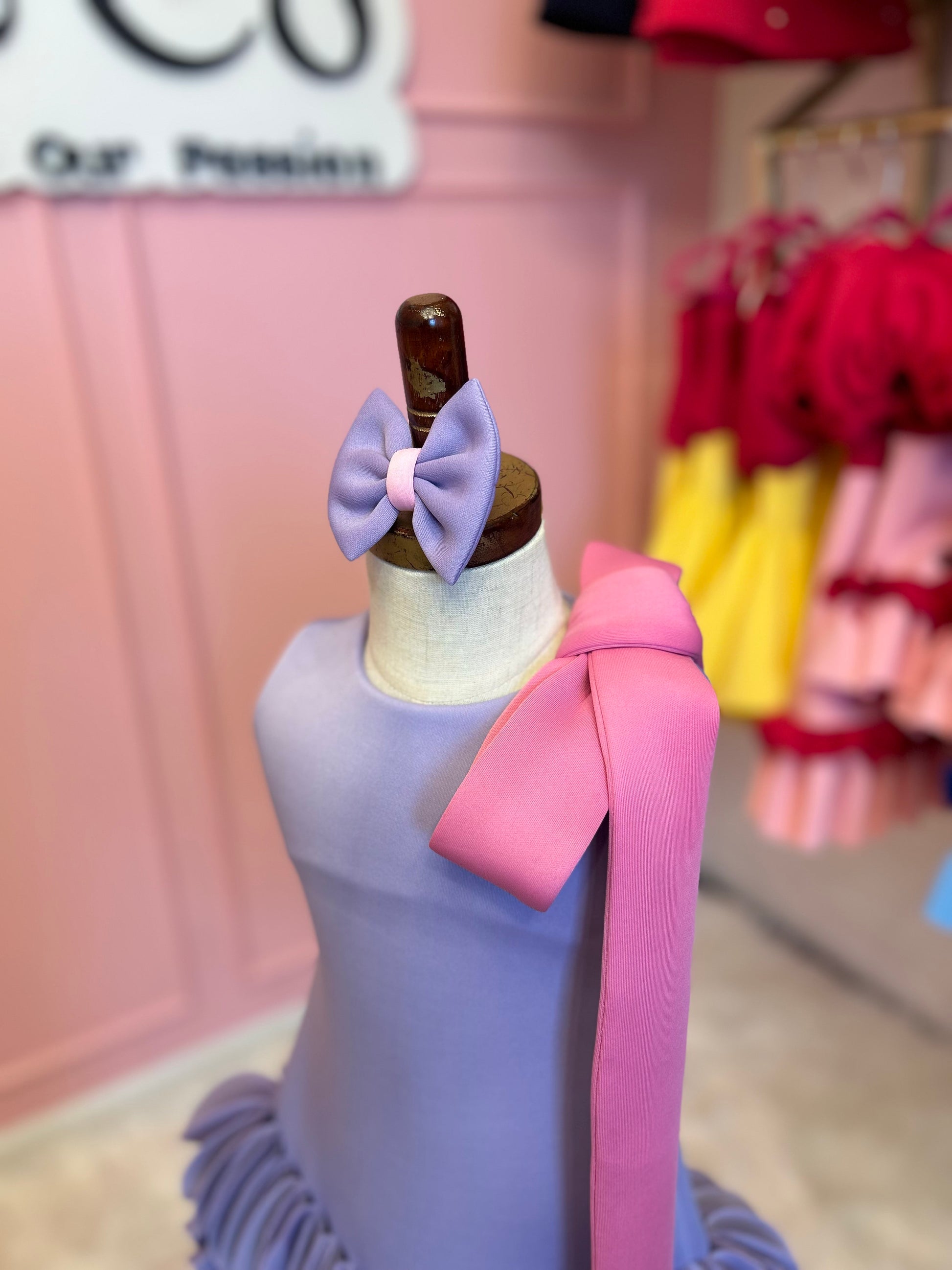 close up of Blue sleeveless straight cut floral dress for kids displayed on a fashion stand, showing pink bow