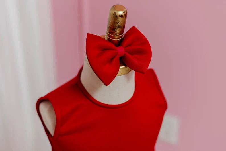 Matching head bow for red block bow dress, displayed on a fashion stand