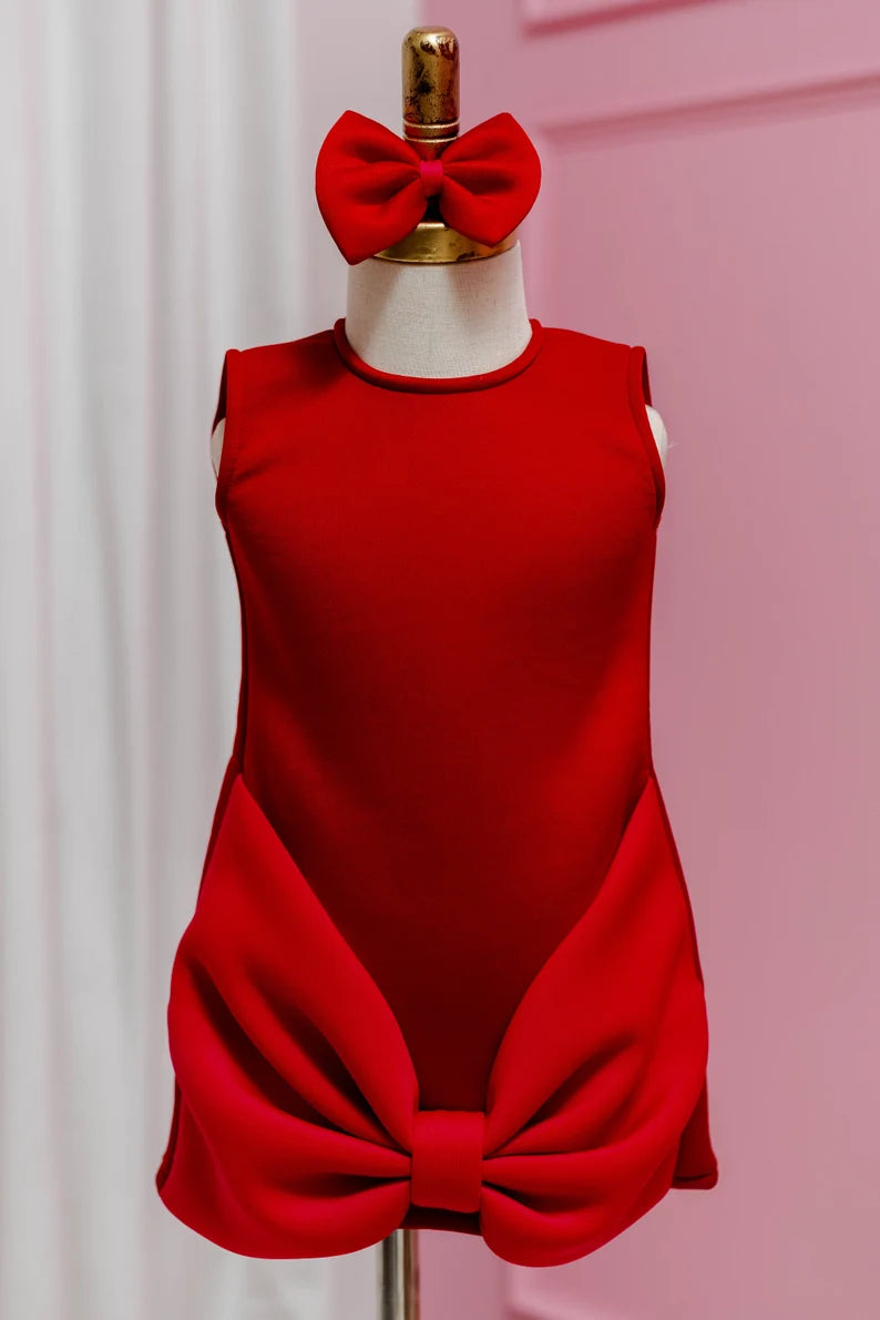 cute red block bow dress with matching head bow displayed on fashion stand