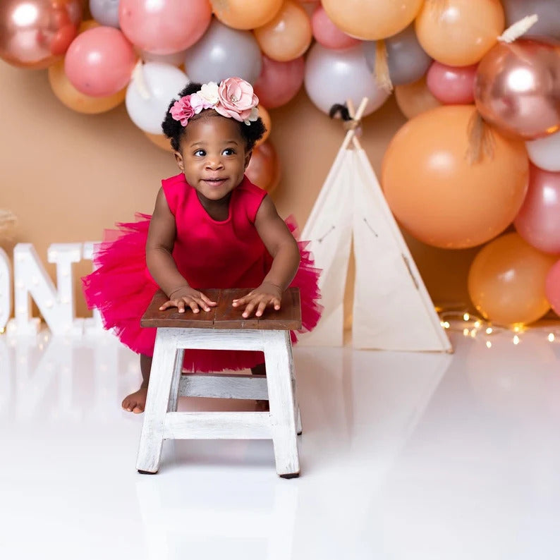 Toddler girl modelling fuchsia pink tulle dress and holding wooden chair