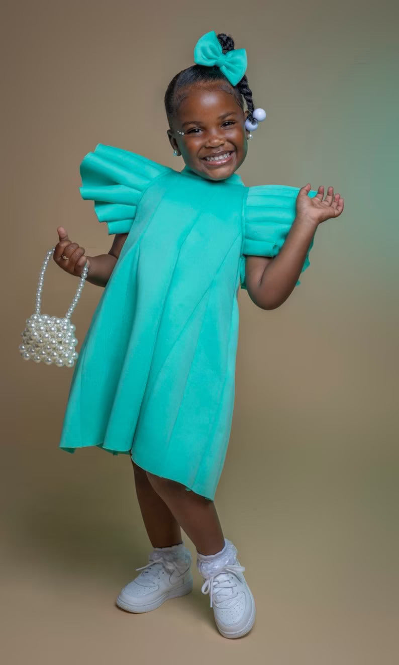 A little girl modelling a Lilac puffy sleeve dress with matching head piece and pearl bag