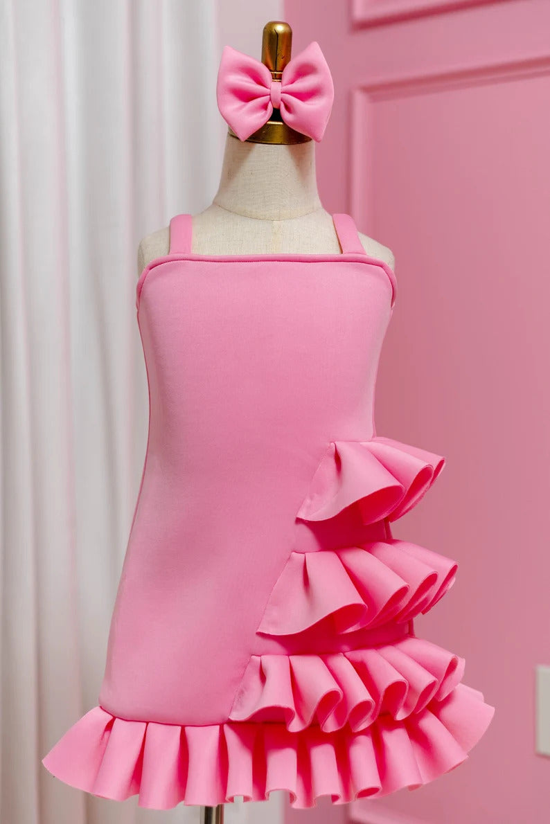 sleeveless pink side ruffle dress with matching bow displayed on fashion stand