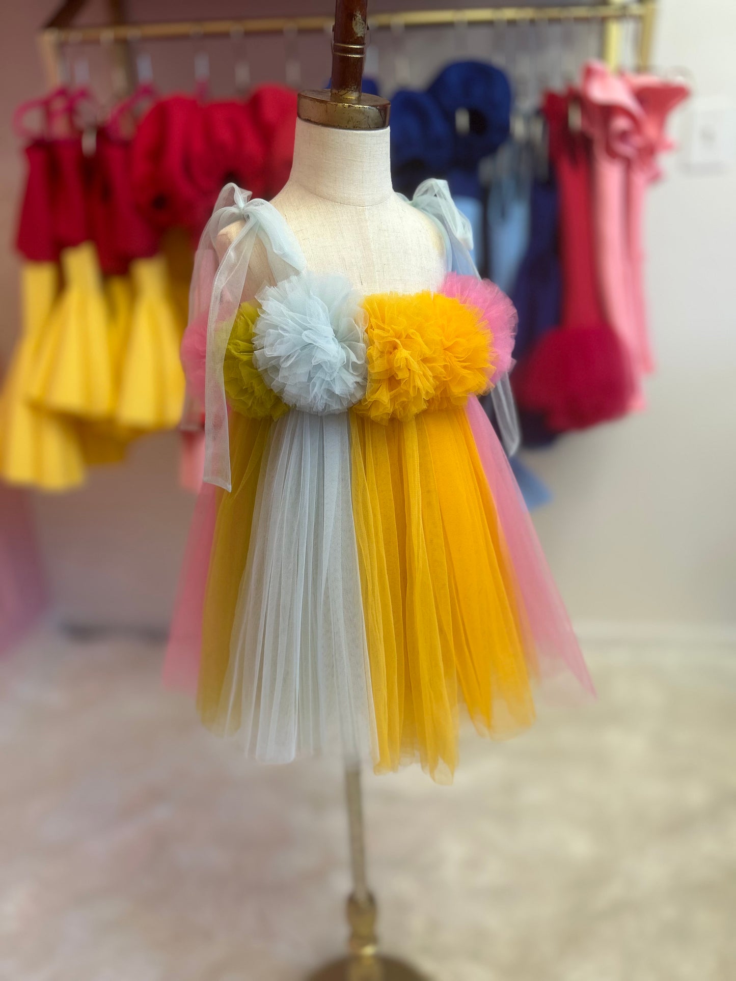 side view multi-coloured dreamy tulle dress for little girl, displayed on fashion stand