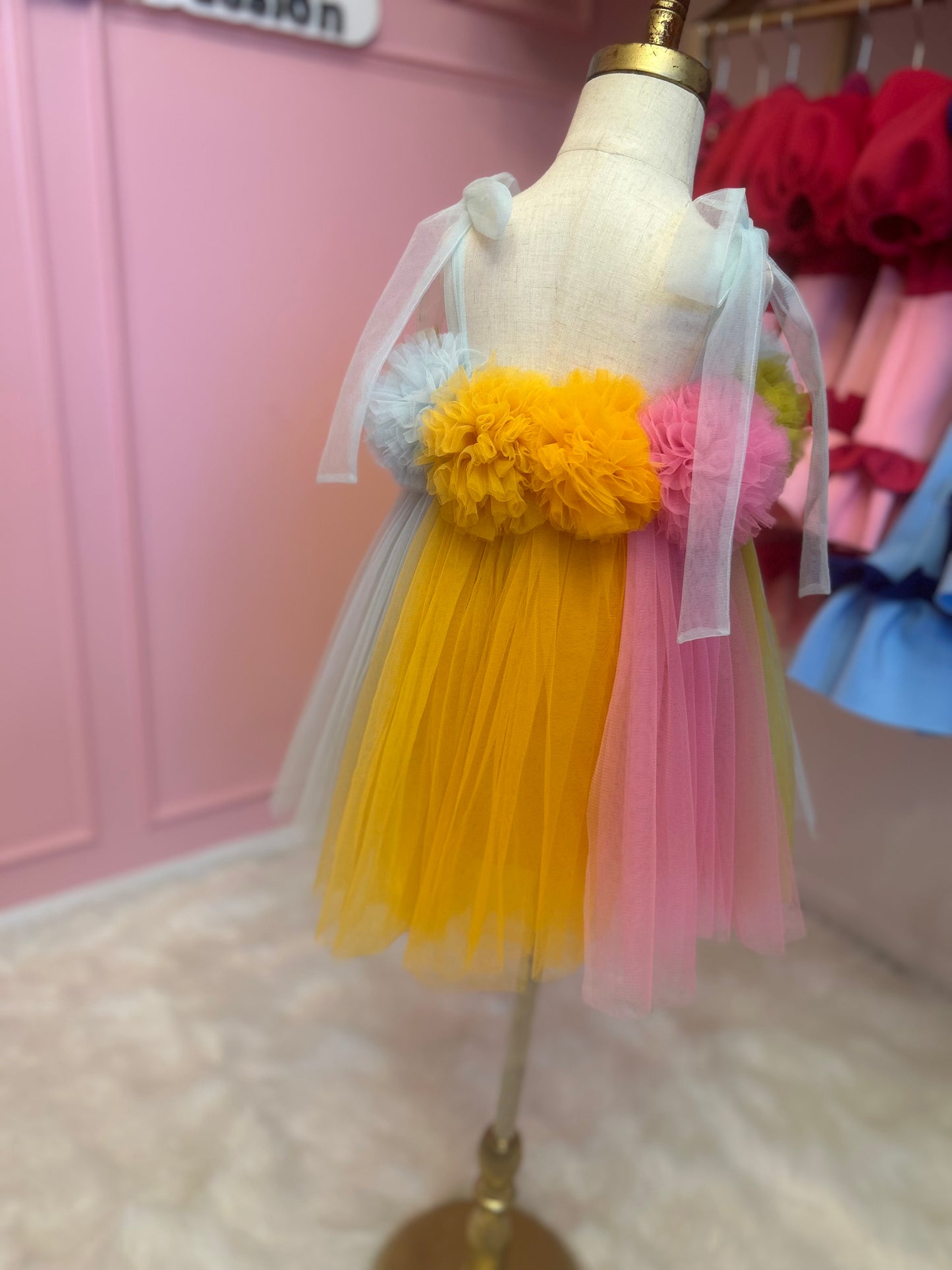 Back view of multi-coloured dreamy tulle dress for little girl, displayed on fashion stand