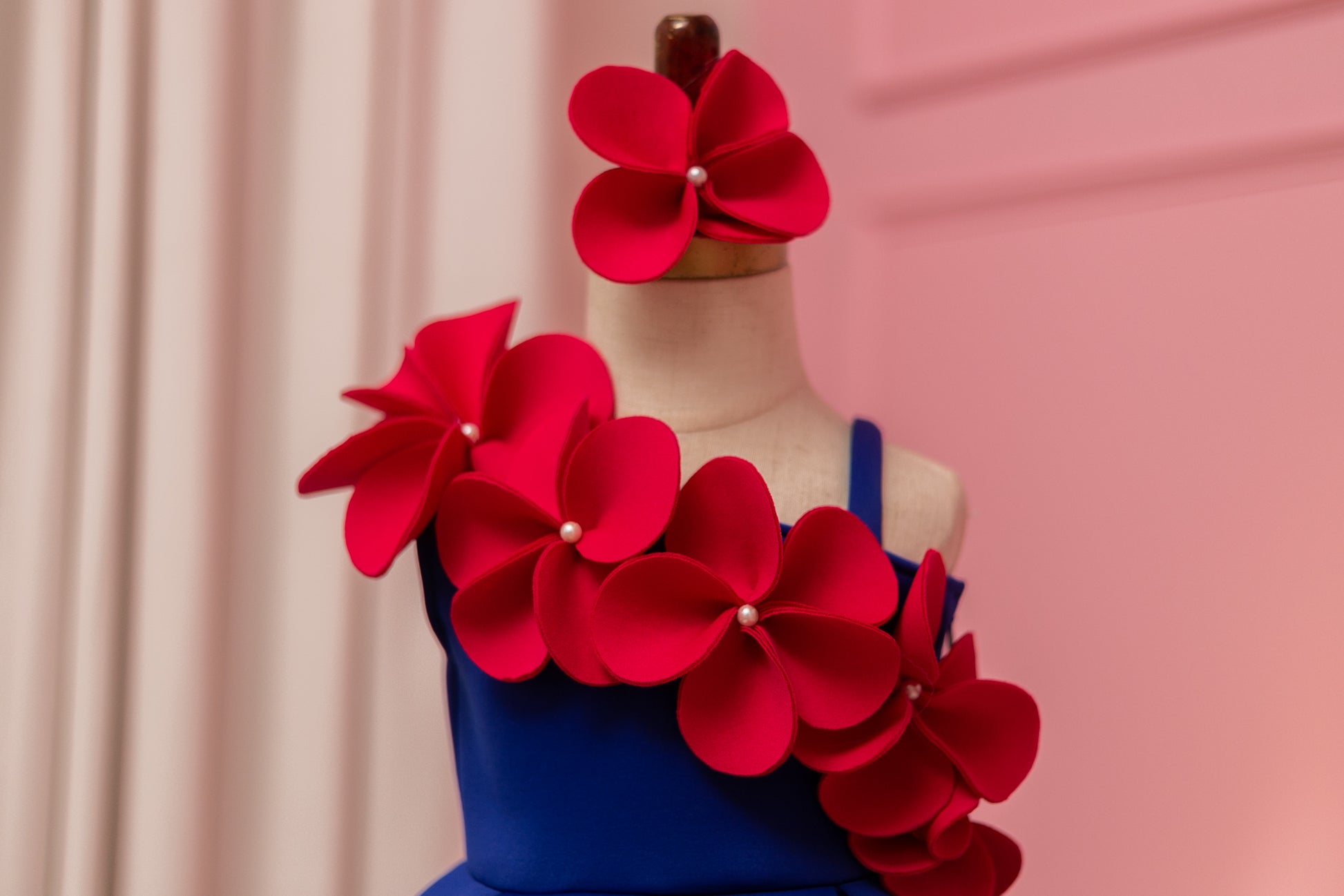 close up showing one shoulder flower dress with matching hair bow