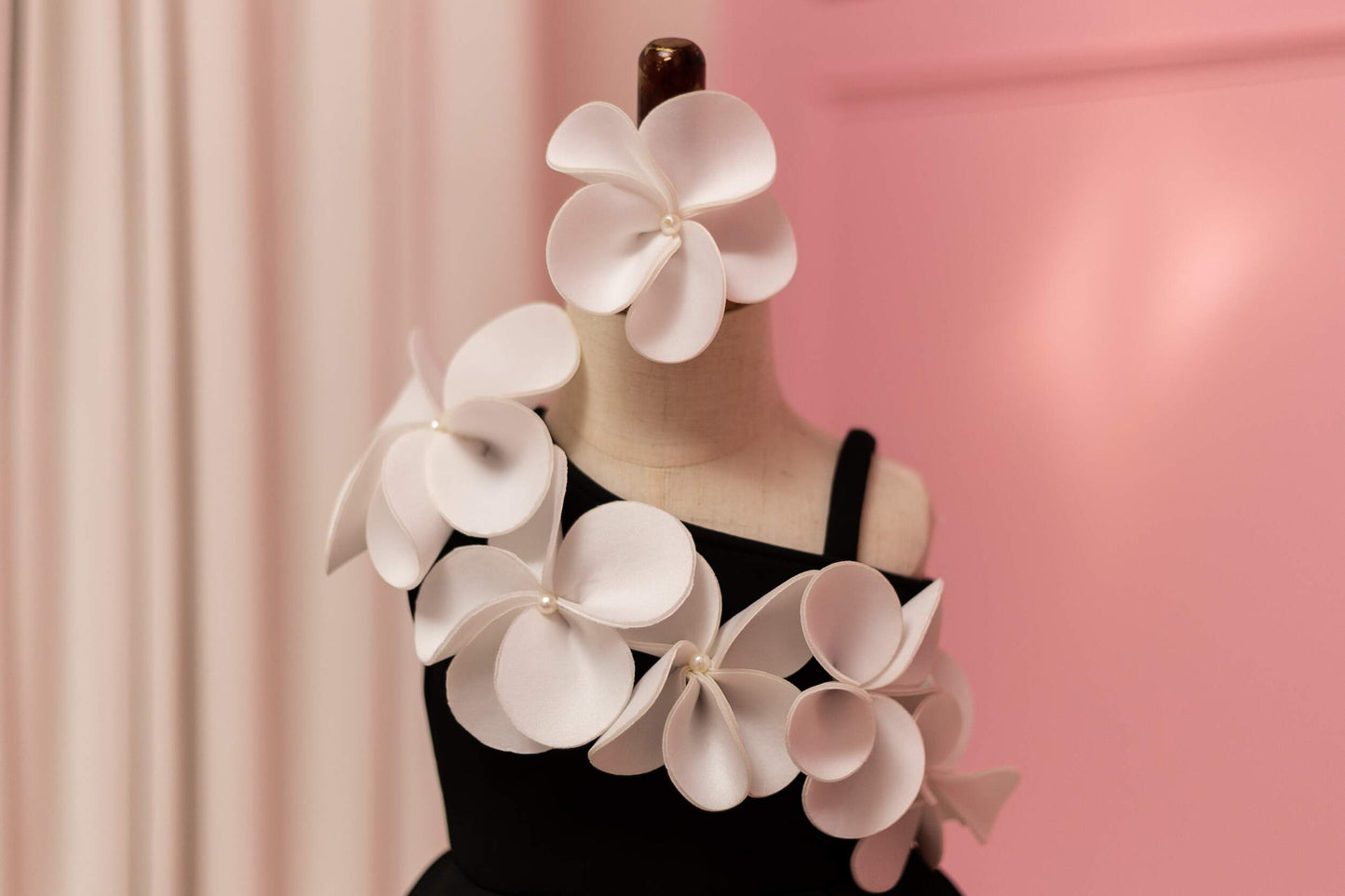 Close up of floral pattern on black dress, displayed on fashion stand