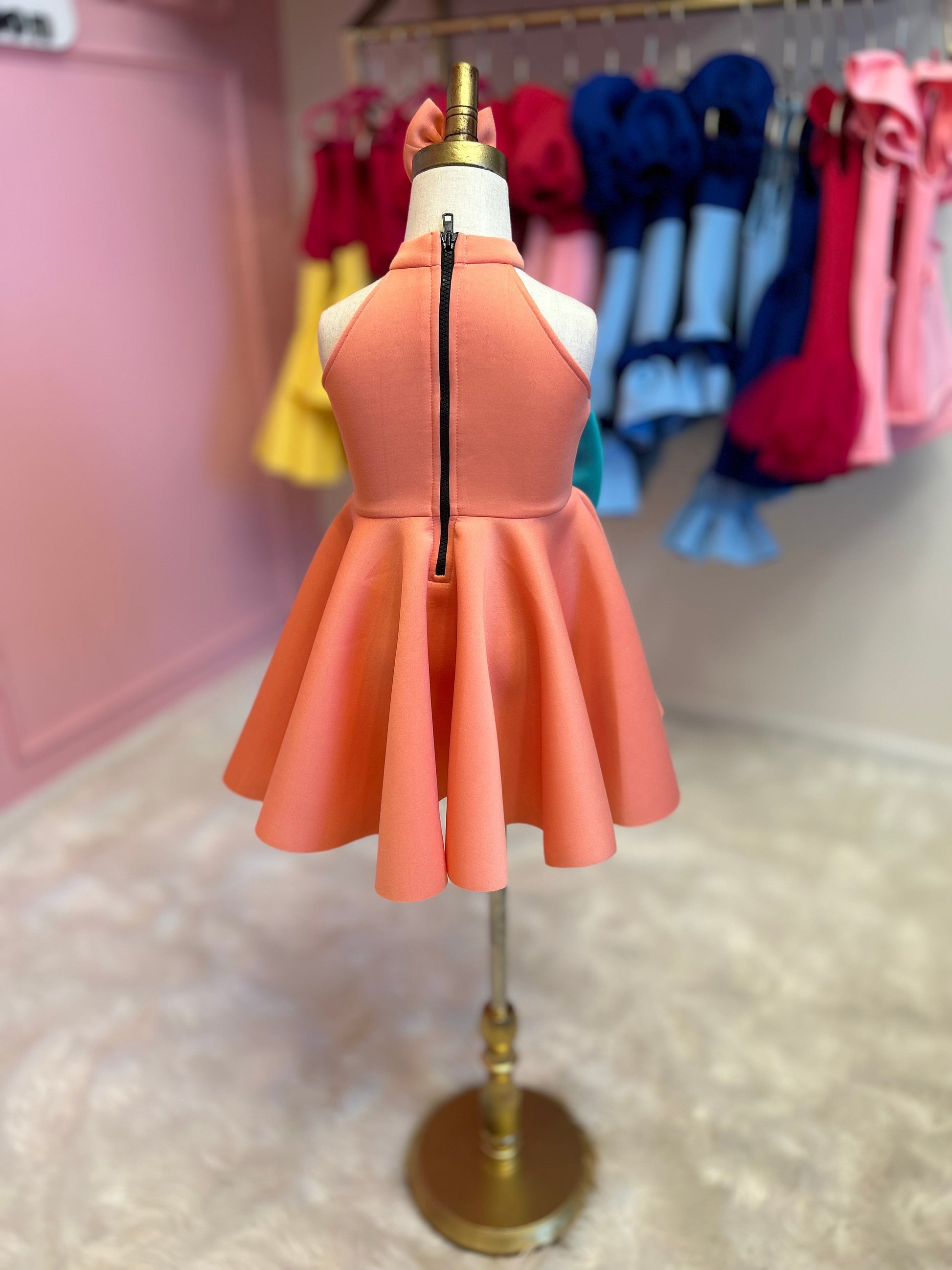 rearview of peach and mint sweet bow dress with matching head piece displayed on fashion stand