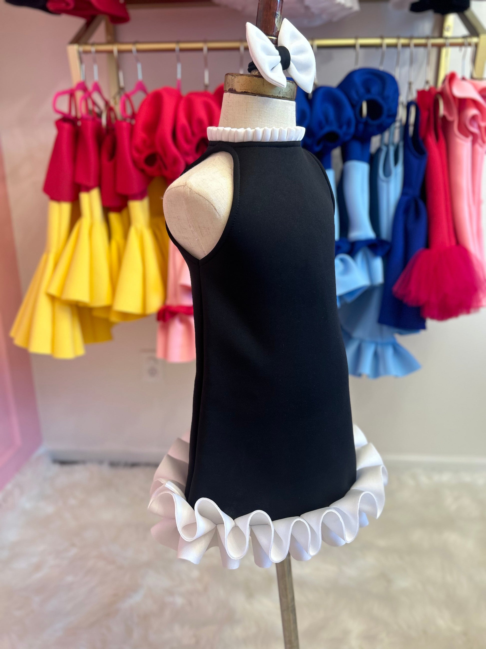 Sideview of Black dress with neckline and base ruffle, displayed on fashion stand