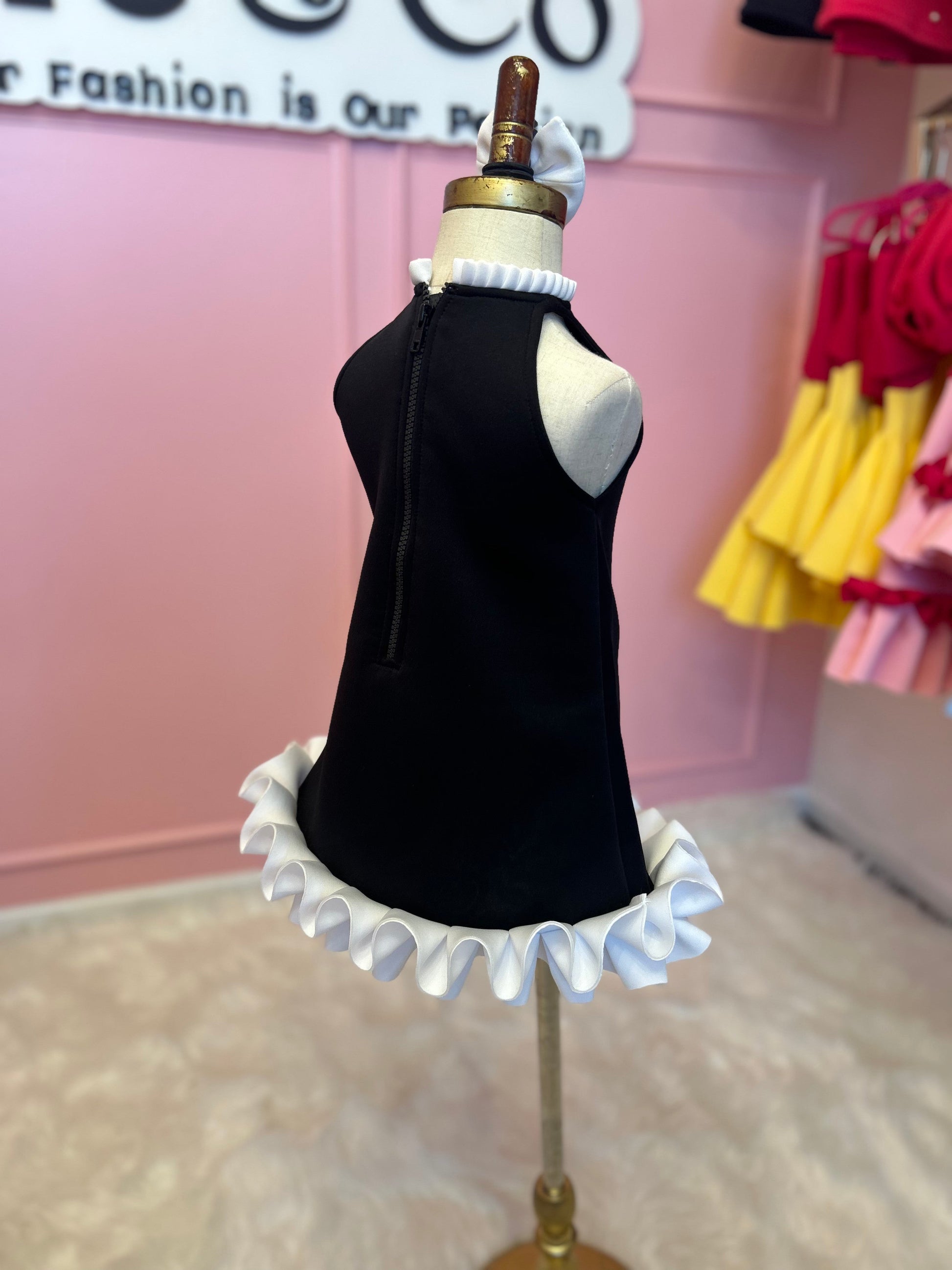 Back view of Sideview of Black dress with neckline and base ruffle, displayed on fashion stand