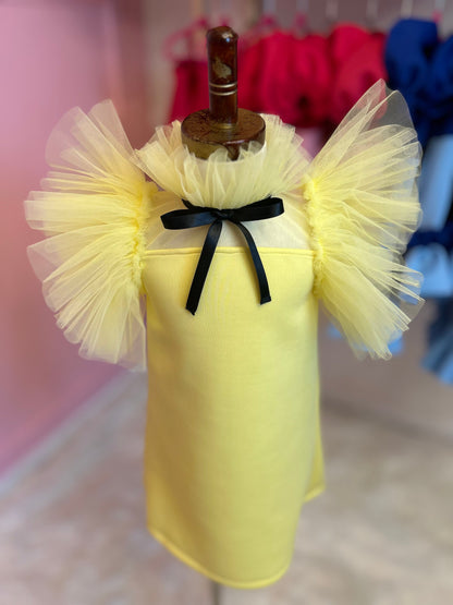 close up of Lemon yellow dress with tulle fluttering around the neck and sleeves, displayed on a fashion stand