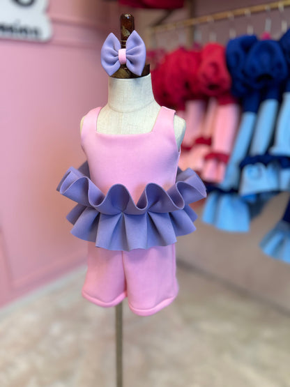 Pink romper with purple ruffles displayed on a fashion stand