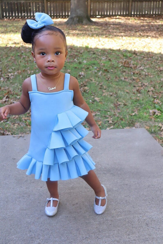 little girl modelling sleeveless sky blue side ruffle dress, with a matching bow