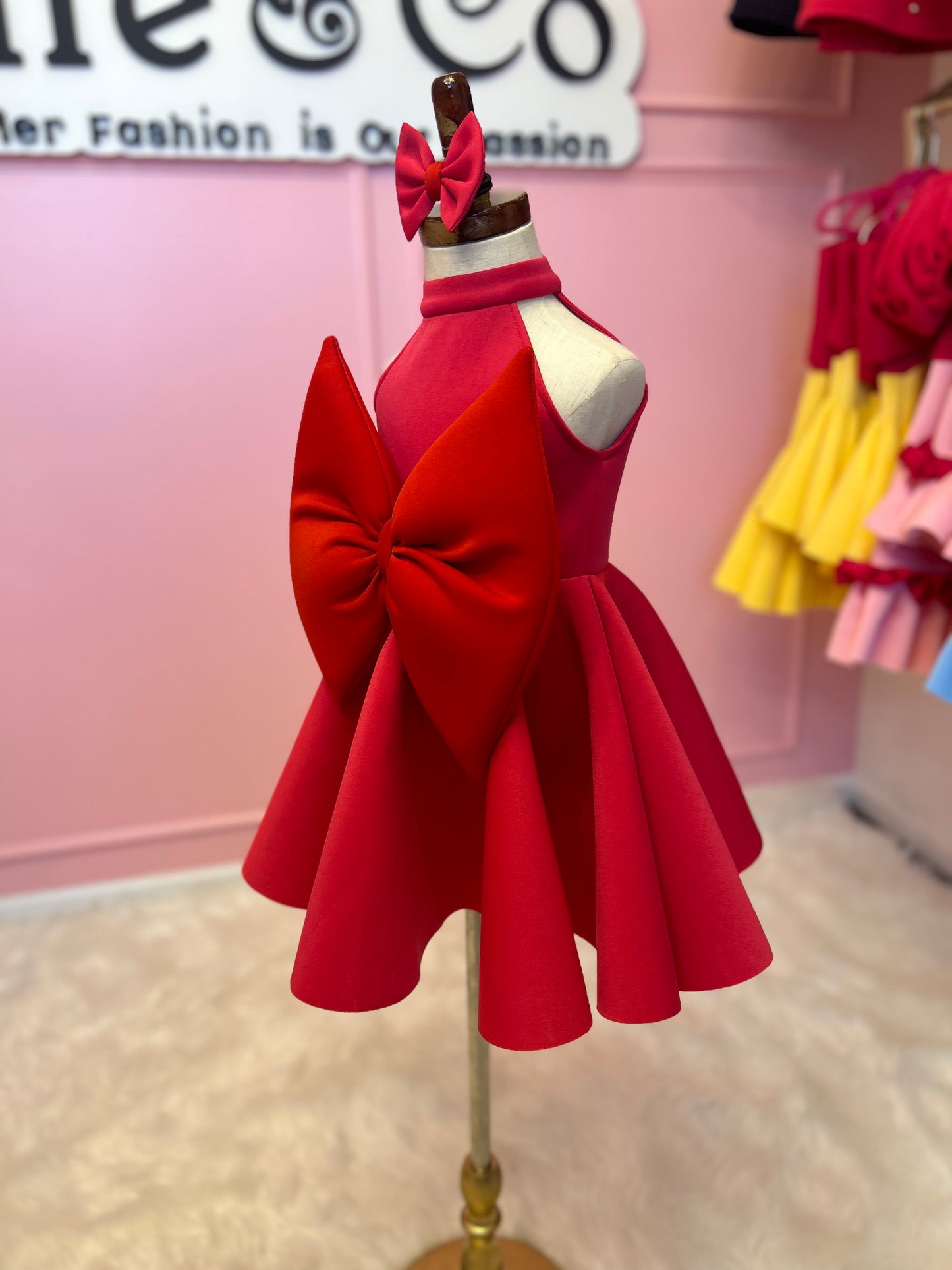 side view of sleeveless halter neck red bow dress displayed on fashion stand